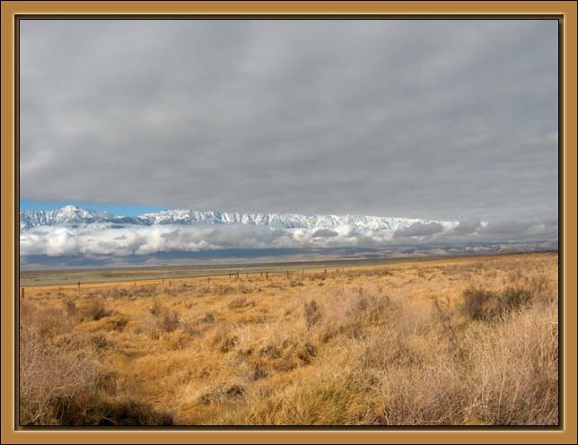 The Sierra Nevada Mountains peep trhough from clouds over the Owens Valley. The High Sierra contains a string of the highest mountains in the contiguous United States, among the m Mt. Whitner.